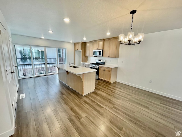 kitchen with an inviting chandelier, a sink, stainless steel appliances, baseboards, and dark wood-style floors