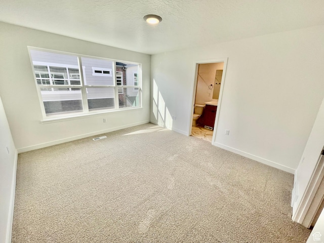 empty room featuring a textured ceiling, baseboards, carpet, and visible vents