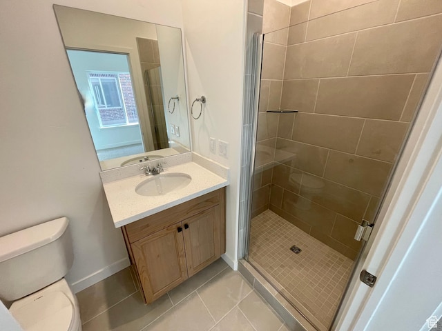 bathroom featuring vanity, tile patterned flooring, toilet, a stall shower, and baseboards