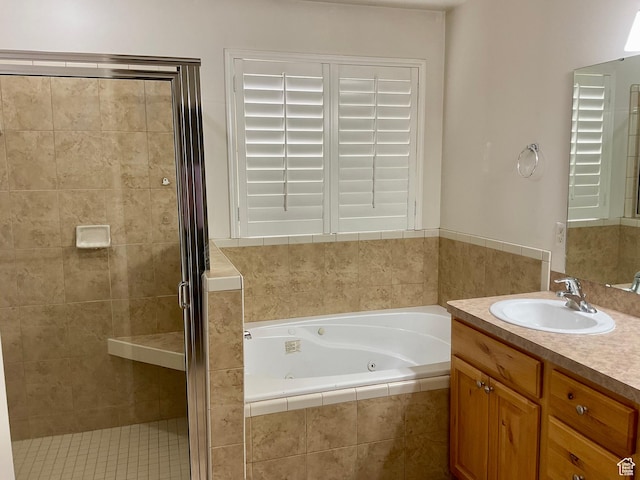 bathroom featuring a tub with jets, a stall shower, and vanity