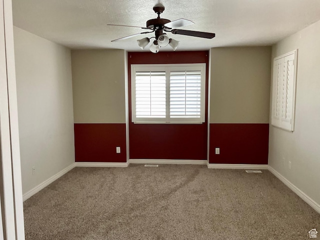 carpeted spare room featuring baseboards and a ceiling fan
