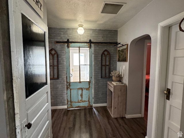 foyer entrance featuring visible vents, baseboards, arched walkways, a barn door, and dark wood-style floors