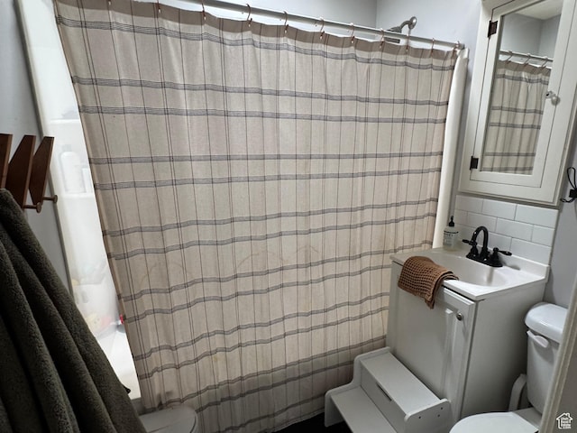 bathroom featuring a sink, tile walls, toilet, and backsplash