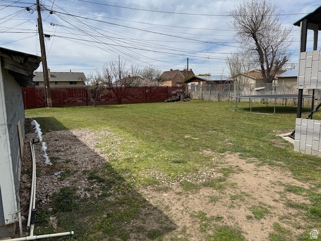 view of yard with a trampoline and a fenced backyard