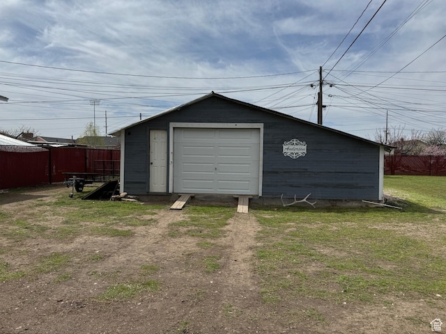 garage with fence and dirt driveway