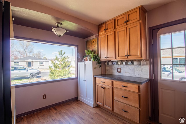 180 E Southgate Ave S, Salt Lake City, UT 84115 - kitchen featuring light wood-style flooring, brown cabinetry, a wealth of natural light, and dark countertops