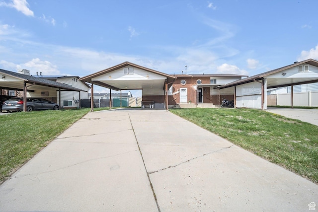 view of front of house featuring driveway, fence, an attached carport, and a front lawn