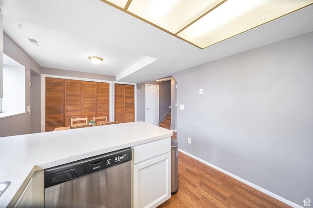 kitchen featuring light wood-style flooring, visible vents, white cabinets, baseboards, and stainless steel dishwasher