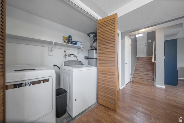 washroom with a textured ceiling, wood finished floors, laundry area, and washing machine and dryer