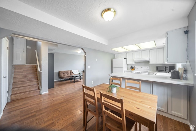 kitchen with dark wood finished floors, under cabinet range hood, stainless steel microwave, light countertops, and electric stove