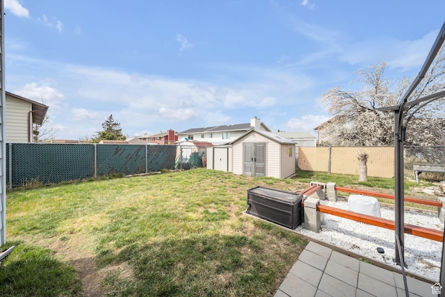 view of yard featuring a storage shed, a fenced backyard, and an outdoor structure
