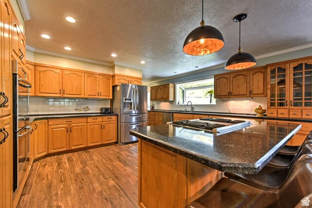 1050 S 200 W, Wellsville, UT 84339 - kitchen featuring ornamental molding, appliances with stainless steel finishes, a breakfast bar, and wood finished floors