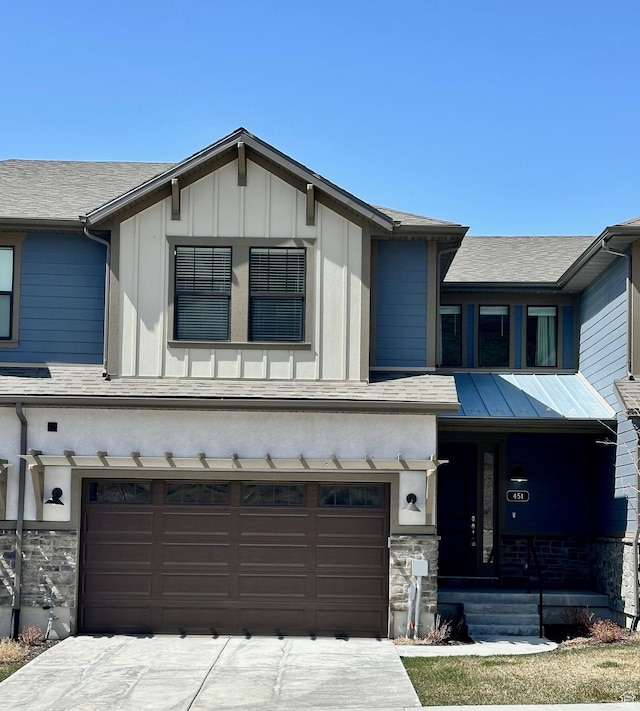 view of front of home with board and batten siding, an attached garage, stone siding, and driveway