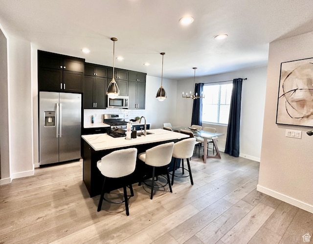 451 W Glenview Loop, Heber City, UT 84032 - kitchen with a chandelier, a center island with sink, light wood finished floors, and stainless steel appliances