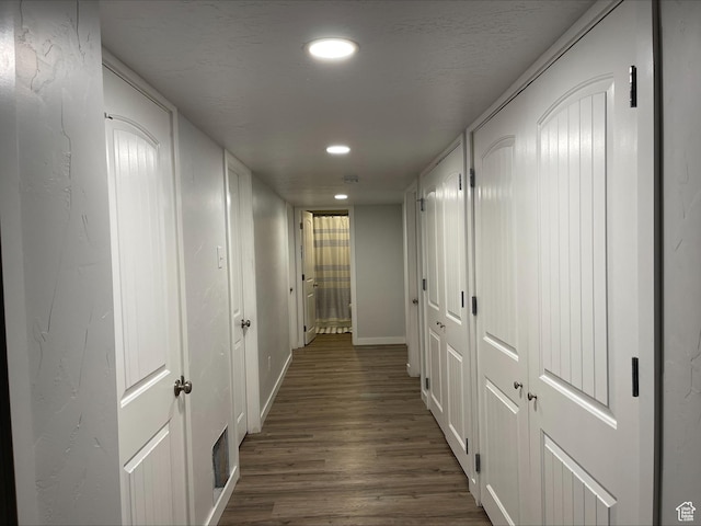 hallway featuring baseboards, recessed lighting, and dark wood finished floors
