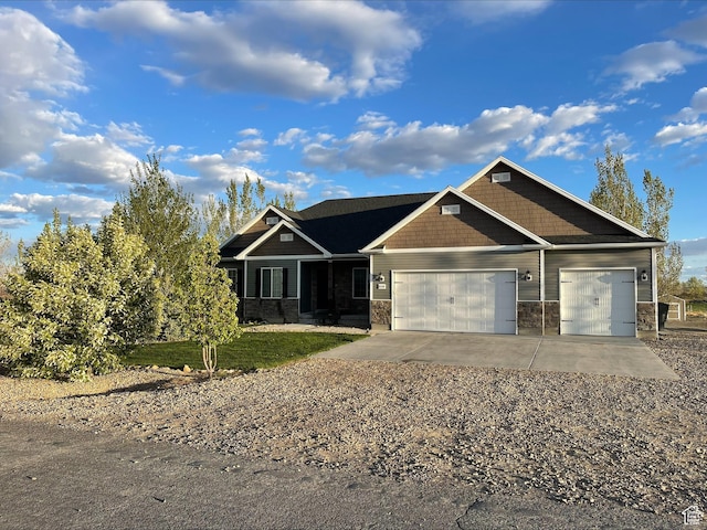 craftsman inspired home with an attached garage, driveway, and stone siding
