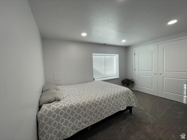 bedroom with dark carpet, recessed lighting, a textured ceiling, and a closet