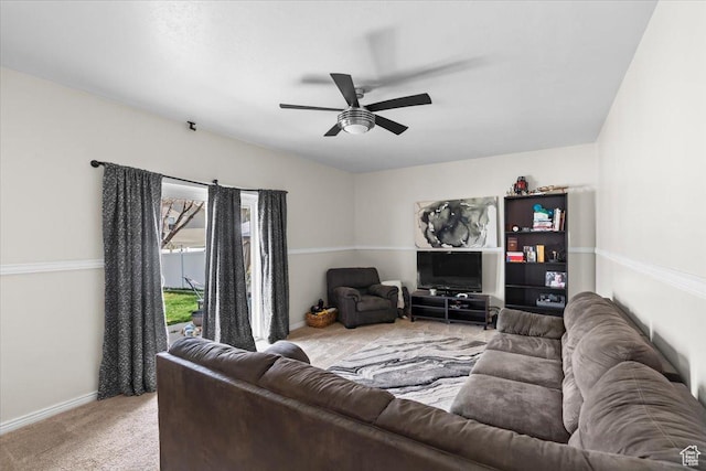 living room with light carpet, baseboards, and a ceiling fan