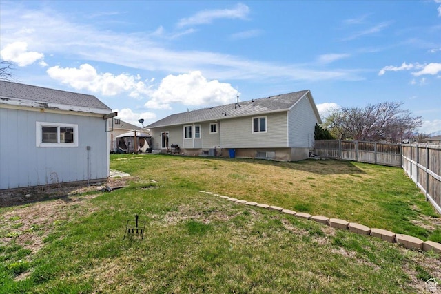 rear view of house with a fenced backyard and a lawn