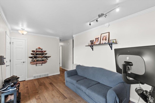 living area with crown molding, wood finished floors, baseboards, and visible vents