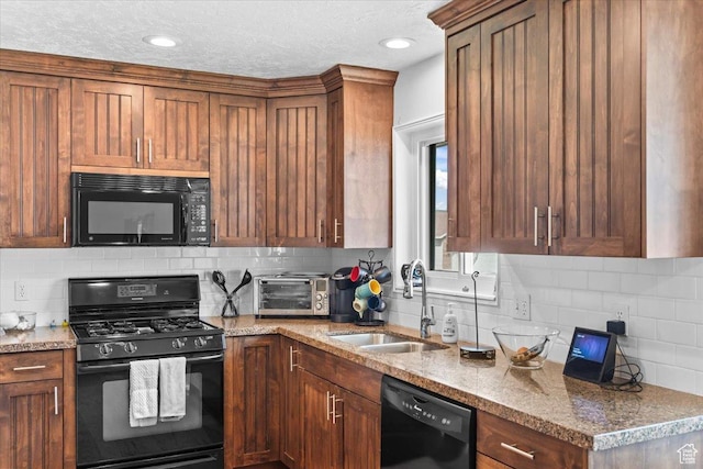 kitchen featuring a sink, backsplash, black appliances, and light stone counters