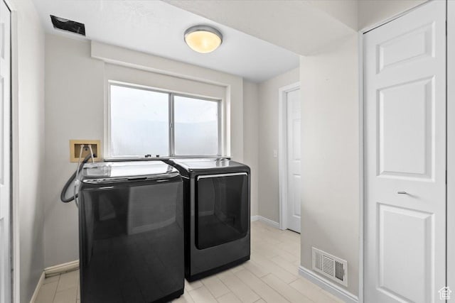 clothes washing area with washer and dryer, visible vents, laundry area, and baseboards