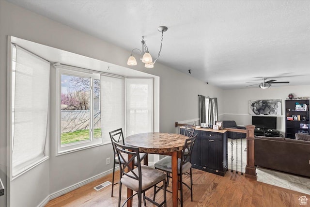 dining room featuring visible vents, baseboards, light wood finished floors, and ceiling fan with notable chandelier