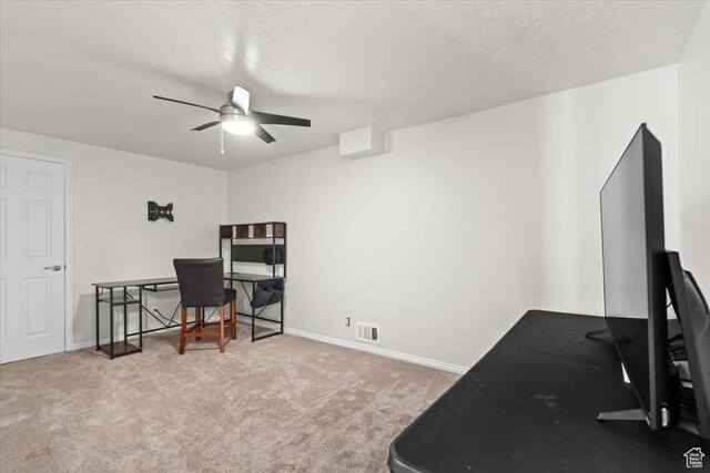 carpeted office space featuring visible vents, baseboards, a textured ceiling, and ceiling fan