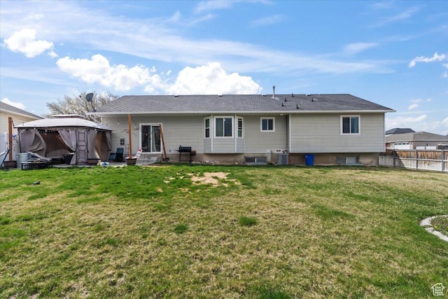 rear view of house featuring fence and a lawn