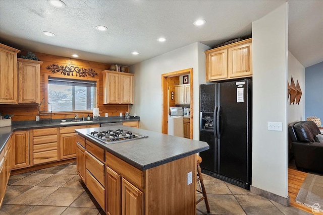 kitchen featuring black fridge, recessed lighting, dark countertops, and a kitchen island