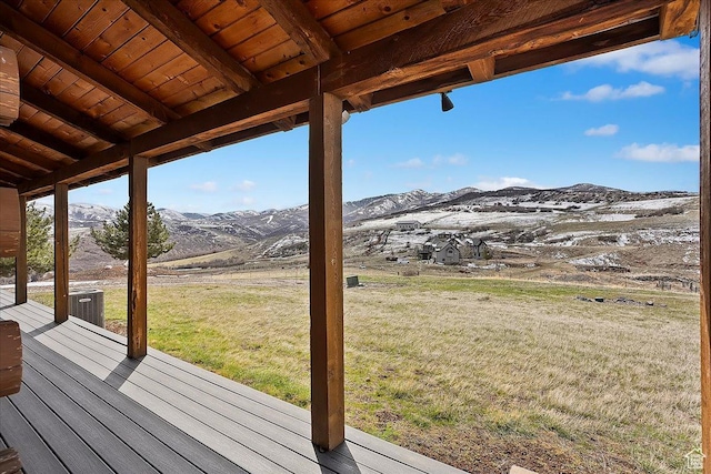 deck featuring central AC, a mountain view, and a lawn