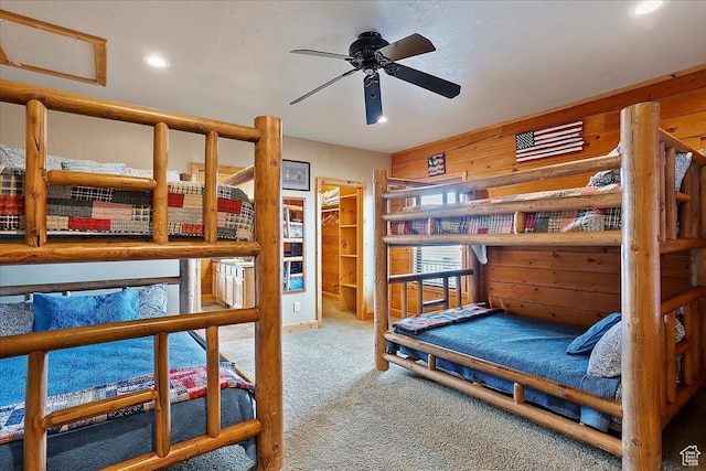 carpeted bedroom featuring wood walls and recessed lighting