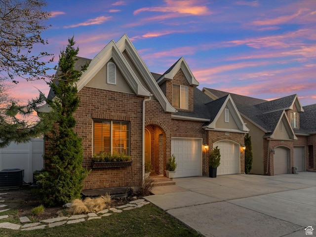 view of front of house with brick siding, fence, central AC, and driveway
