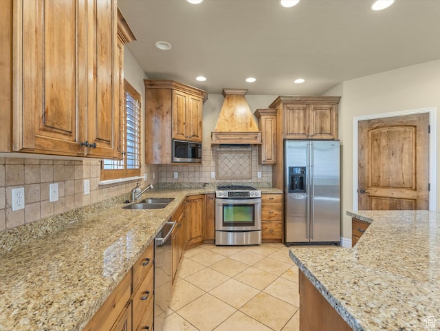 kitchen with a sink, custom range hood, brown cabinetry, and appliances with stainless steel finishes