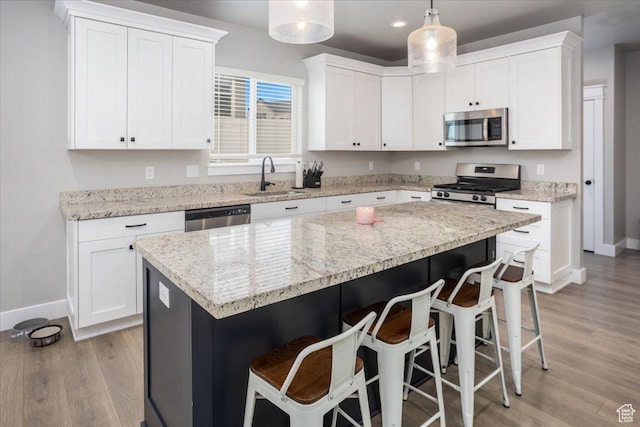 1379 E Hollyhock Ct, Layton, UT 84040 - kitchen with a sink, light wood-style floors, white cabinetry, stainless steel appliances, and a breakfast bar area