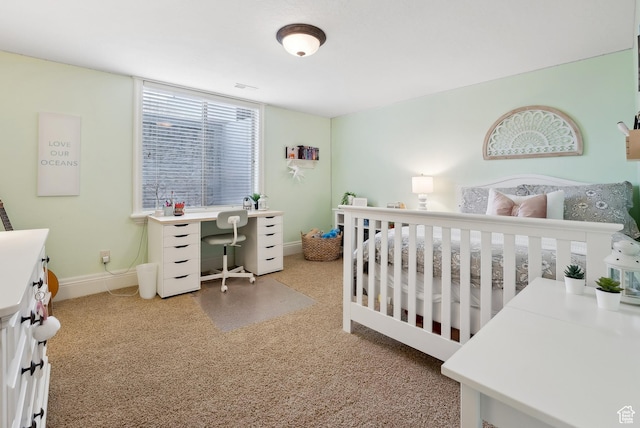 carpeted bedroom with baseboards and a crib