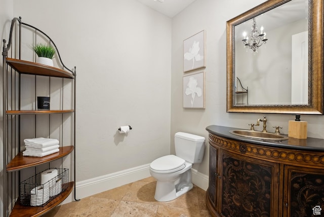 half bathroom featuring vanity, toilet, baseboards, and a chandelier