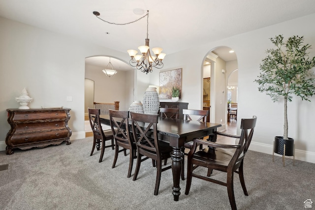 dining room featuring carpet, a chandelier, baseboards, and arched walkways