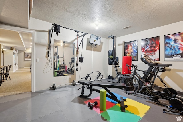 workout room featuring a textured ceiling, visible vents, and baseboards
