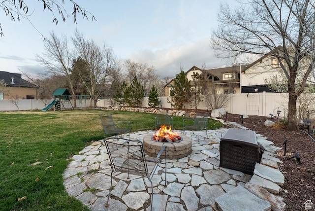 view of yard with a fenced backyard, an outdoor fire pit, a playground, and a patio