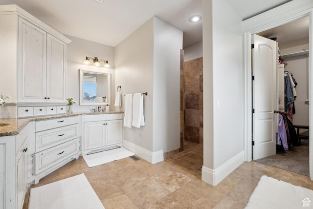 bathroom with a walk in closet, visible vents, baseboards, walk in shower, and vanity