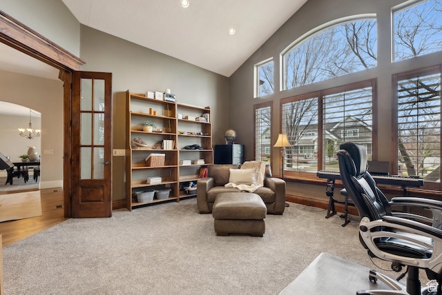 office featuring carpet flooring, a chandelier, a healthy amount of sunlight, and high vaulted ceiling