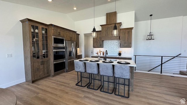 427 E Redwood Ln Unit 120, Grantsville, UT 84029 - kitchen featuring stainless steel appliances, backsplash, a breakfast bar, light wood-style floors, and lofted ceiling