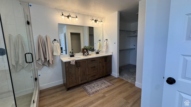 427 E Redwood Ln Unit 120, Grantsville, UT 84029 - bathroom featuring wood finished floors, double vanity, a stall shower, a walk in closet, and a textured ceiling