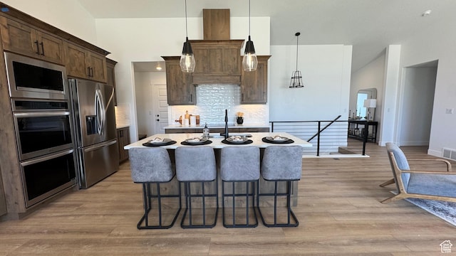 427 E Redwood Ln Unit 120, Grantsville, UT 84029 - kitchen featuring appliances with stainless steel finishes, dark brown cabinets, a kitchen breakfast bar, light wood-type flooring, and an island with sink