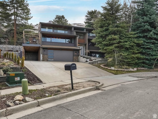 view of front of home featuring a garage, stone siding, driveway, and a balcony