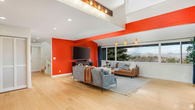 living room with a wealth of natural light, light wood finished floors, baseboards, and stairway