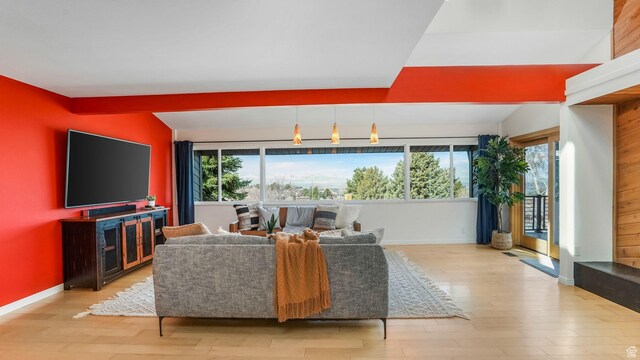 living area with lofted ceiling, baseboards, and wood finished floors