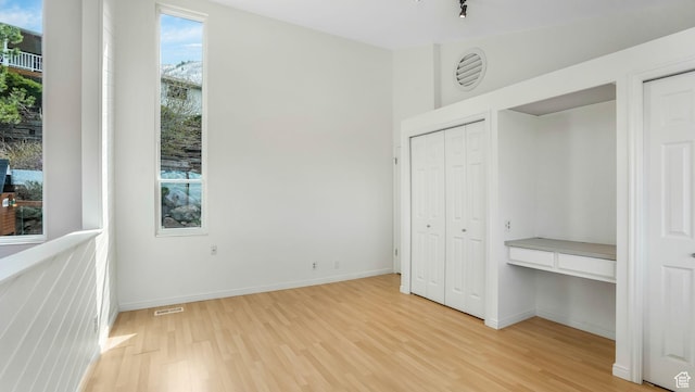 unfurnished bedroom with visible vents, baseboards, two closets, and light wood-style floors