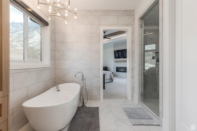 bathroom with a freestanding tub, a notable chandelier, tile walls, ensuite bath, and marble finish floor